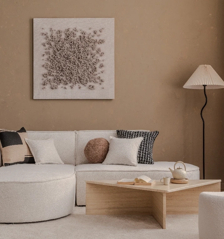 Beige målad vägg med vit soffa, golvlampa och hylla